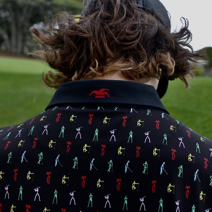 The back of a black polo with a vibrant pattern of colorful stick figure golfers, showing the embroidered logo on the back of the collar.