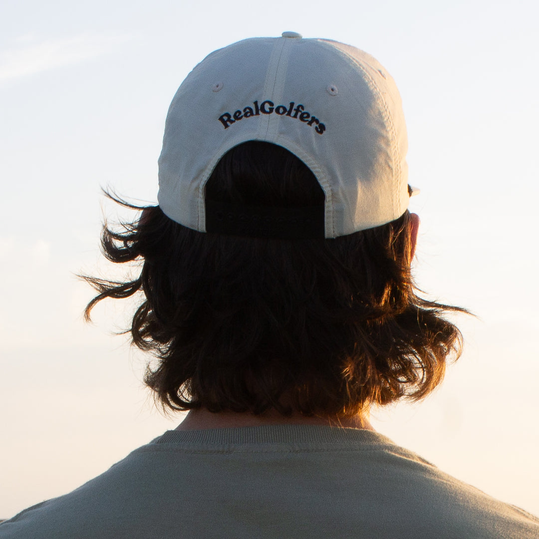 A golfer wearing the white performance golf hat from behind.