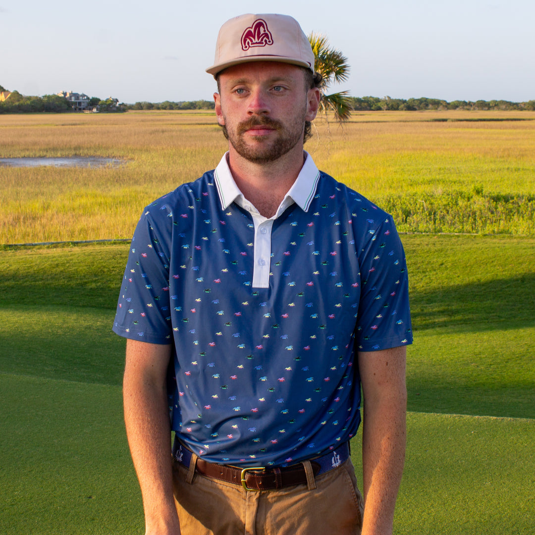 A golfer wearing a blue polo looks at the hole he has just played.