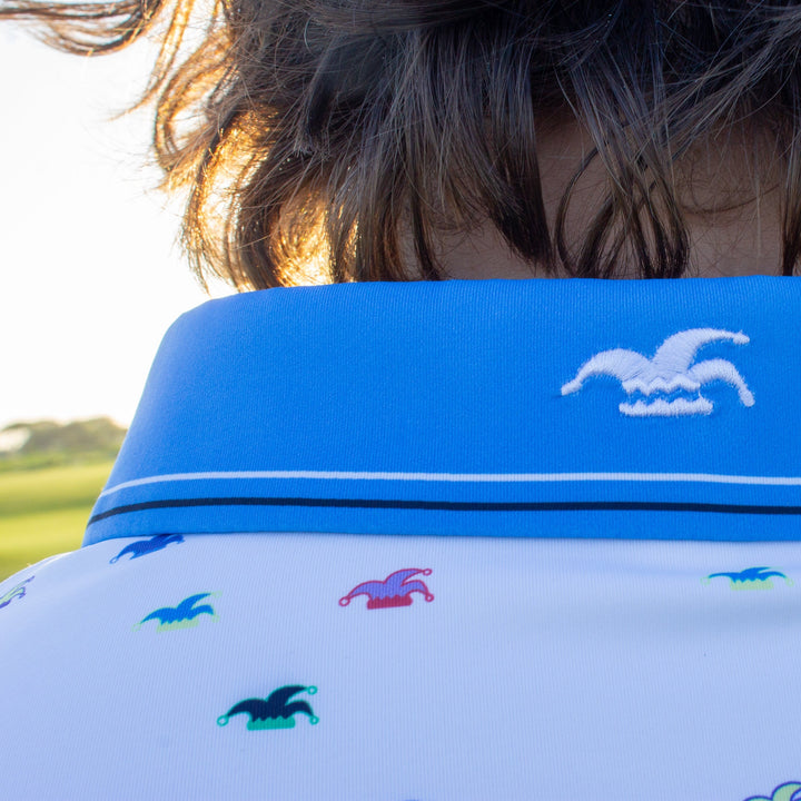 A close up of an embroidered logo on the back of the collar of a polo.