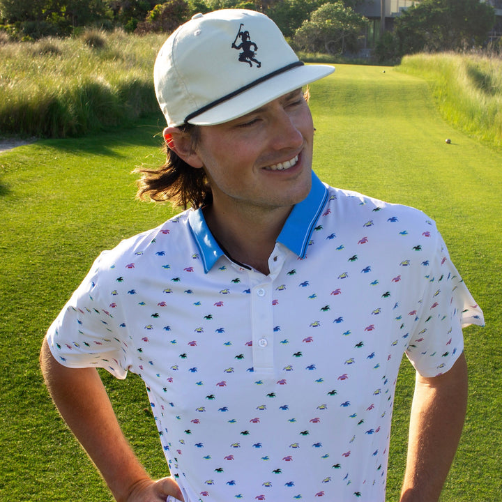 A Golfer wearing a white polo smiles on the golf course.