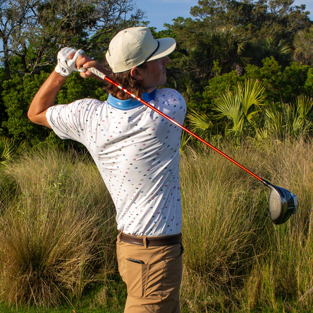 A golfer watches his tee shot soar through the air.