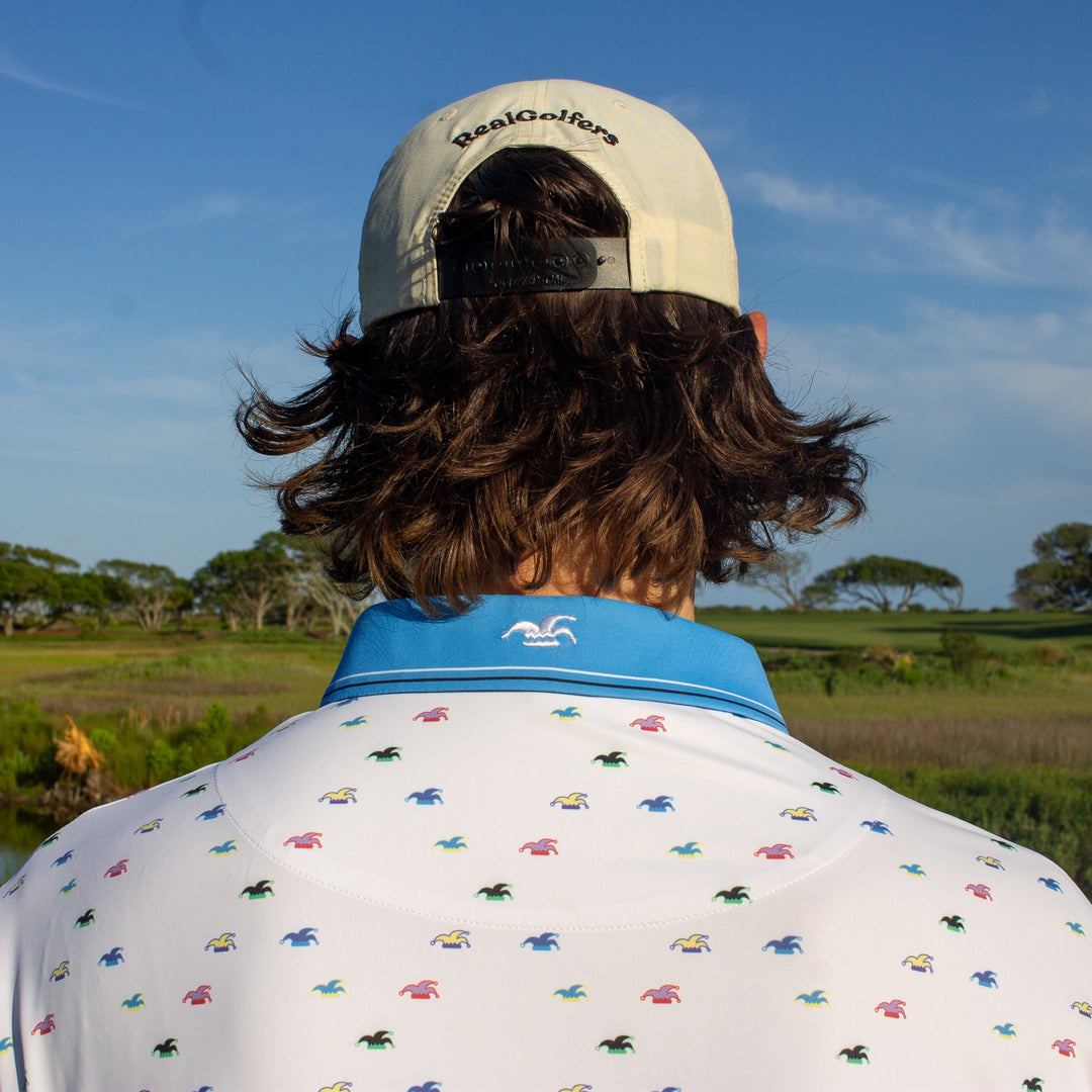 White performance golf polo with a blue collar and an embroidered logo on the back of the collar.